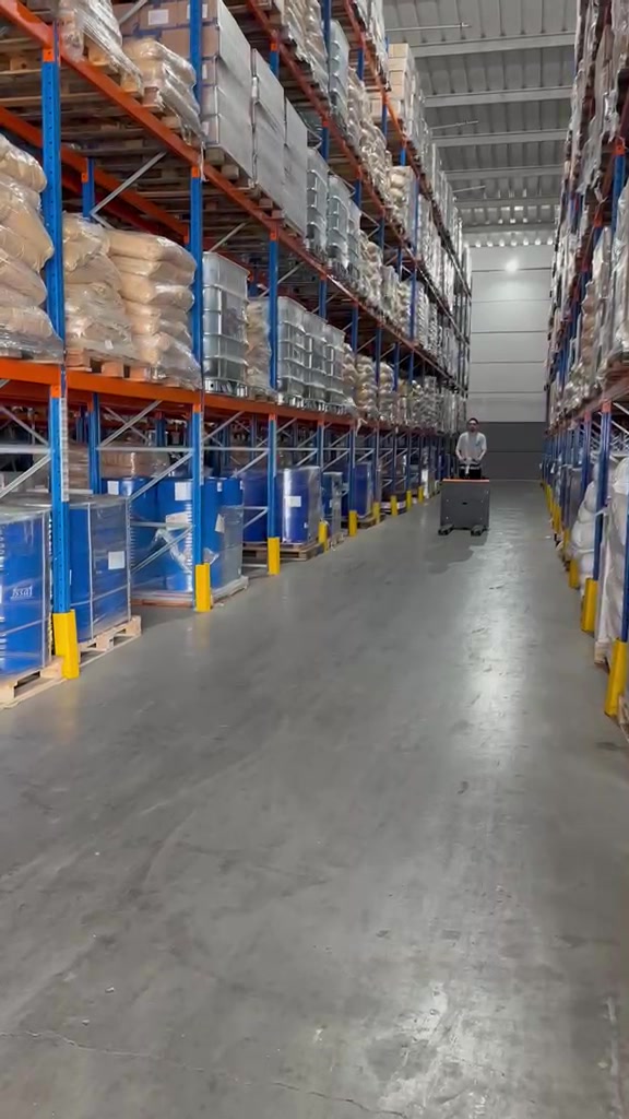 Corredor da LR com mercadorias em porta-paletes e operador ao fundo
