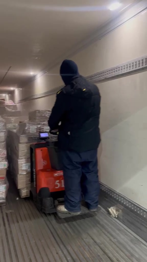 Operador conduzindo paleteira com mercadorias dentro de uma carroceria